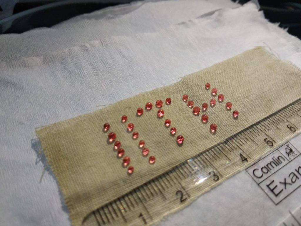 Colored water droplets perched atop a cloth piece treated with the super hydrophobic fly ash